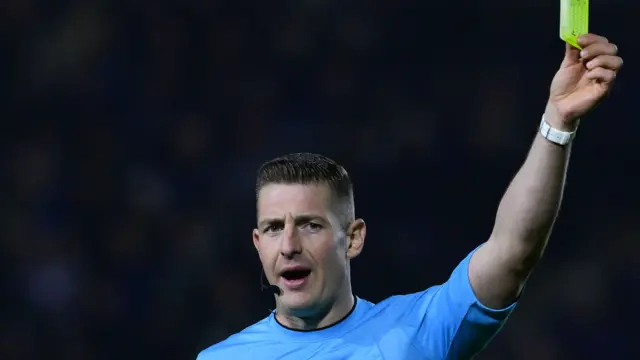 Referee Robert Jones shows the yellow card