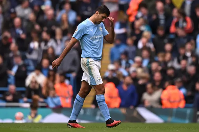 Rodri wipes his head as he trudges off the pitch.