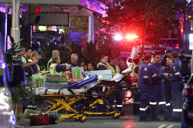 A person is moved to an ambulance surrounded by first responders