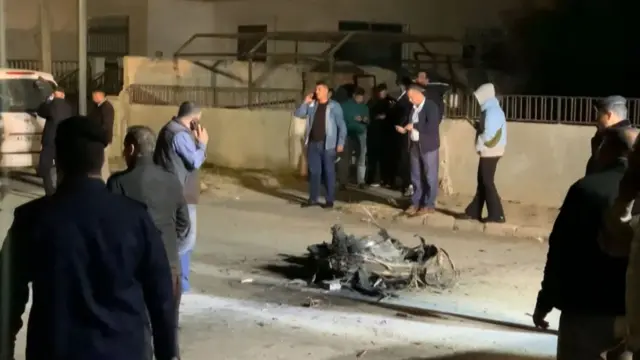 Jordanian onlookers and security agents standing around the debris of a projectile that the Jordanian forces intercepted over Amman