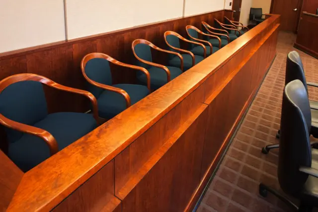 Image of empty jury seats in a nondescript courtroom