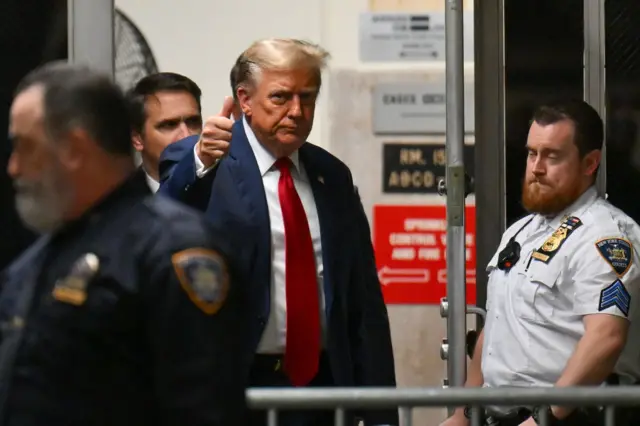 Donald Trump gives a thumbs up as he walks to the courtroom