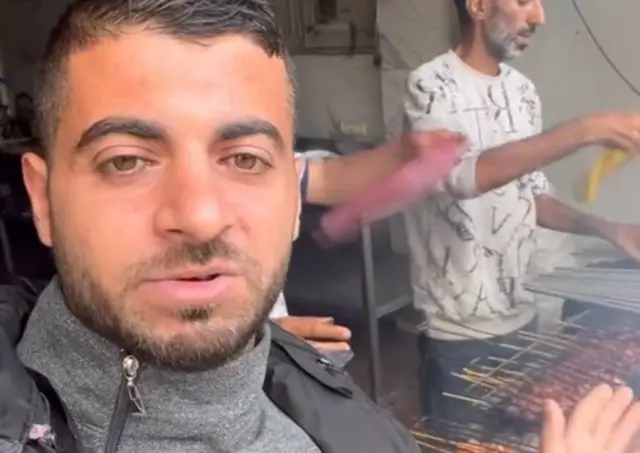 Local activist Hussein Odeh films meat being cooked at a market in northern Gaza