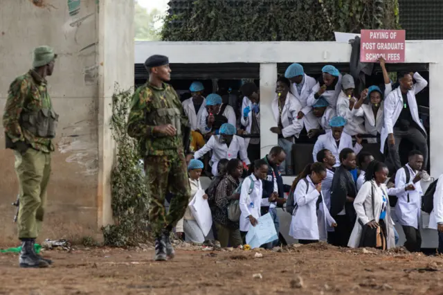 Kenyan police officers keep a watch as doctors take to the streets protesting with placards to demand better pay and working conditions in the capital, Nairobi on April 9, 2024.