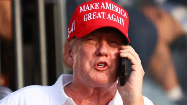 Former US President Donald Trump speaks on the phone at the 18th green during day three of the LIV Golf Invitational - Miami at Trump National Doral Miami on 7 April 2024