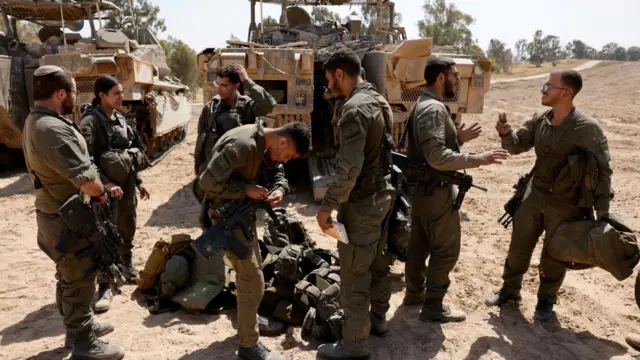 Israeli soldiers stand next to military vehicles, near the Israel-Gaza border, amid the ongoing conflict between Israel and the Palestinian Islamist group Hamas, in Israel, April 15, 2024.