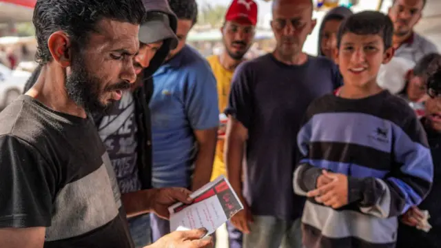 A man reads a leaflet in Arabic designating the northern Wadi Gaza area as a "dangerous combat zone"