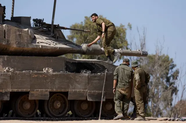 Israeli troops are seen on a tank stationed near the Israel-Gaza border