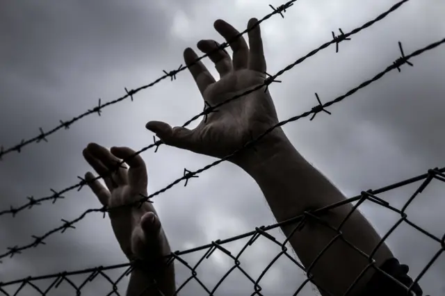 Hands on barb wire - stock photo