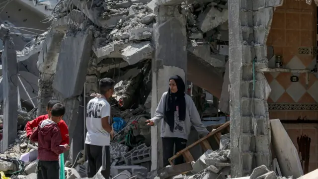 Palestinian families inspect their destroyed houses in Al Maghazi refugee camp, central Gaza Strip, 15 April 2024