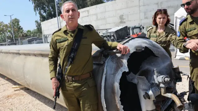 An Israeli military spokesman stands next to what Israel says is the remains of a intercepted Iranian ballistic missile