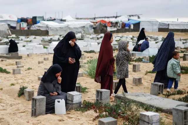 Palestinian women visit graves of people who were killed in the ongoing conflict between Israel and Palestinian Islamist group Hamas, on the day of Eid al-Fitr, in Rafah, in the southern Gaza Strip April 10, 2024