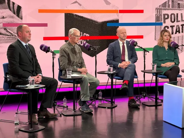 Four people in chairs in studio