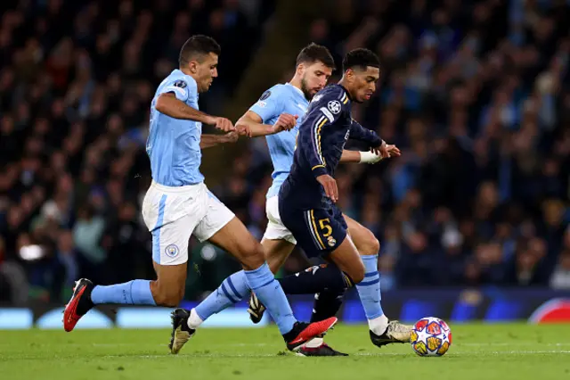 Jude Bellingham of Real Madrid is chased down by Ruben Dias and Rodri