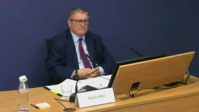 A man sitting at a desk at the Post Office inquiry