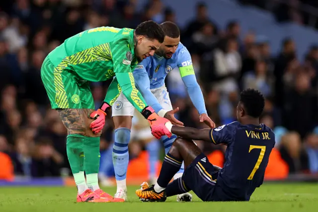 Vinicius Junior of Real Madrid (R) is helped to his feet by Ederson (L) and Kyle Walker