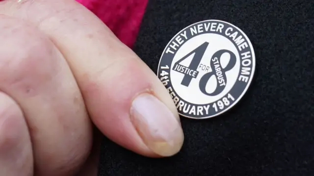 A pin saying They never Came Home. Justice for the Stardust 48