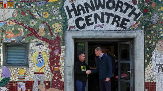 Prince William stands outside the Hanworth Centre shaking a man's hand