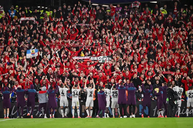 Fans of Bayer Leverkusen celebrate with the players at full-time