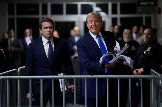 Donald Trump brandishes news articles outside court