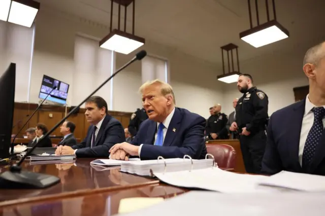 Trump sits in court with other legal staff around him