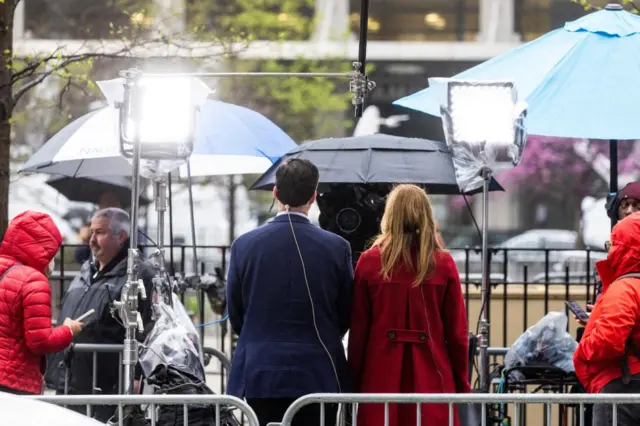 Two reporters standing in front of cameras and bright lights