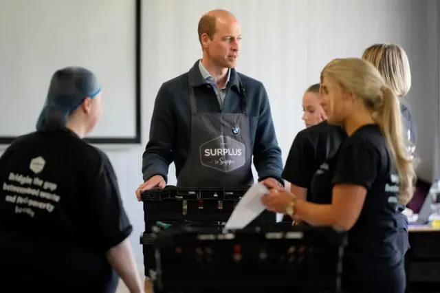 Prince William standing with members of the charity in front of crates