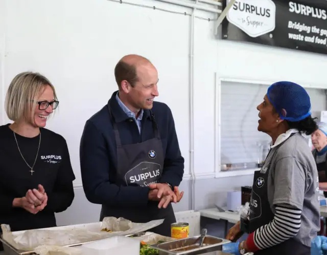 Prince William smiling and talking to charity volunteer Rachel Candappa