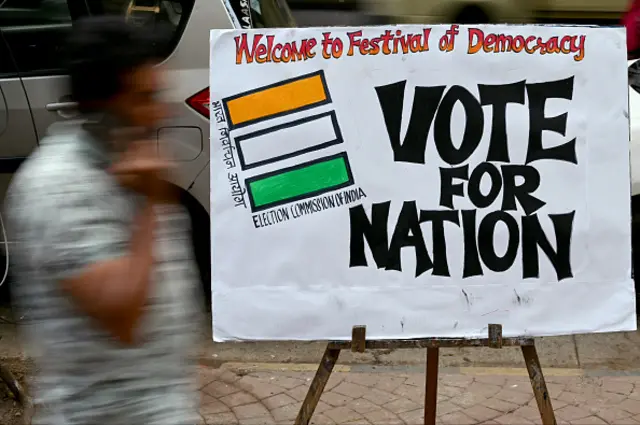 A pedestrian walks past an election themed painting placed by art students along a street outside their class to encourage people to vote in India's upcoming general elections, in Mumbai on April 17, 2024.