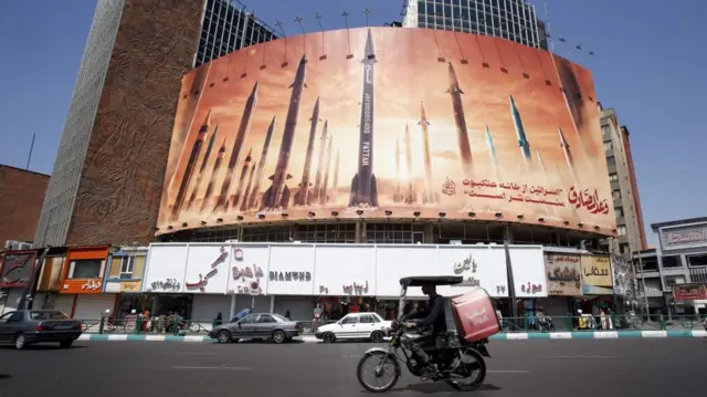 A motorcyclist rides past an anti-Israel billboard in Iran