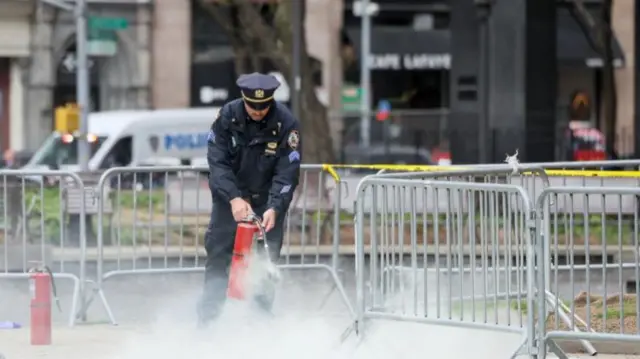 A police officer extingushes the last remaining flames after an unknown man set himself on fire outside the courthouse where Donald Trump's hush-money trial is under way.