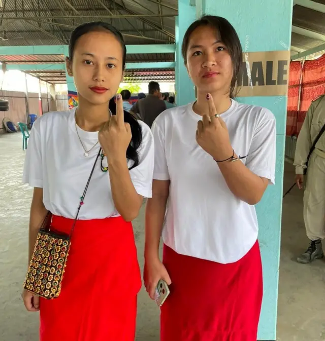 Two first-time voters show their inked fingers after casting their vote at a polling booth in Manipur