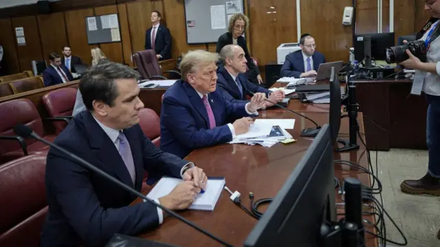 Donald Trump and his lawyers sit at the defence table in court