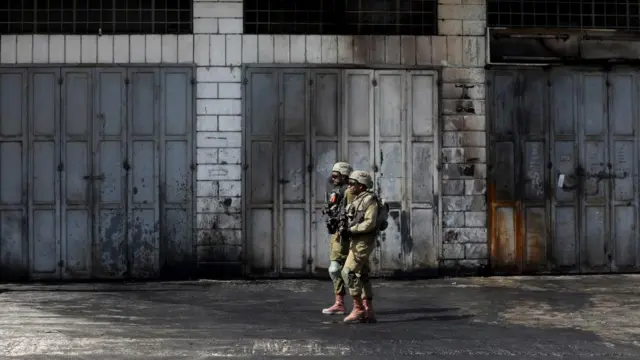 Israeli soldiers patrol closed Palestinian shops in the West Bank town of Hawara, near the city of Nablus