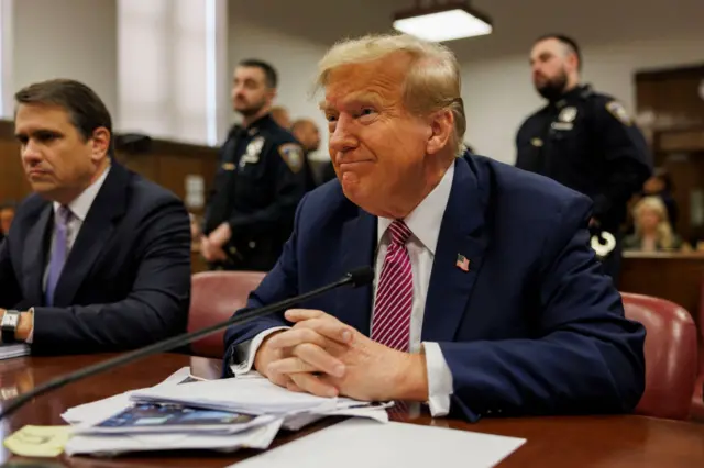 Donald Trump sits in court with his hands clasped