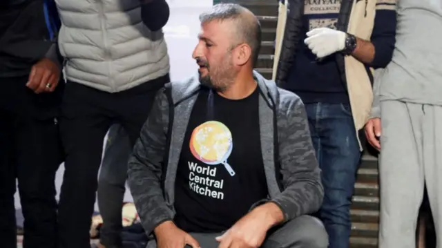 A man in a World Central Kitchen tshirt at a hospital, near the bodies of the killed aid workers