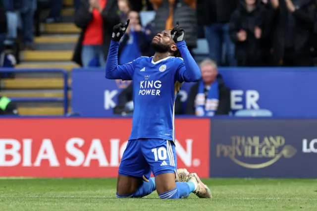 Stephy Mavididi kneels down and points to the sky to celebrate scoring a goal