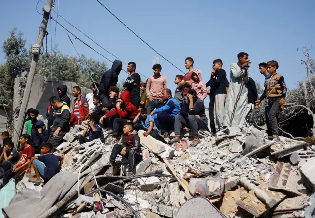 Dozens of people stood on top of rubble