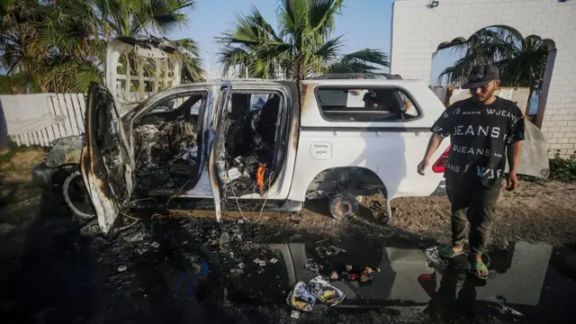 Man stands next to burnt out vehicle belonging to World Central Kitchen in Gaza (02/04/24)