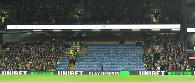 Fans are mved from the stand under a leak in the roof