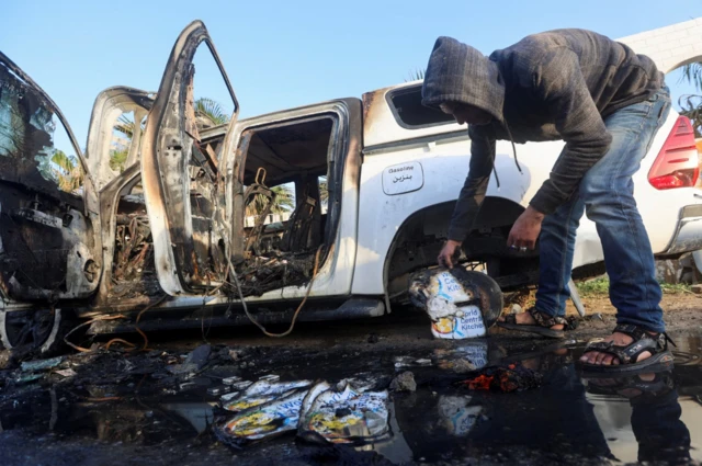 A Palestinian inspects near a vehicle where employees from the World Central Kitchen (WCK), including foreigners, were killed in an Israeli airstrike, according to the NGO as the Israeli military said it was conducting a thorough review at the highest levels to understand the circumstances of this "tragic" incident, amid the ongoing conflict between Israel and Hamas, in Deir Al-Balah