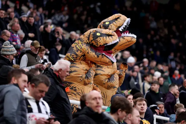 Two Newcastle fans dressed as dinosaurs/