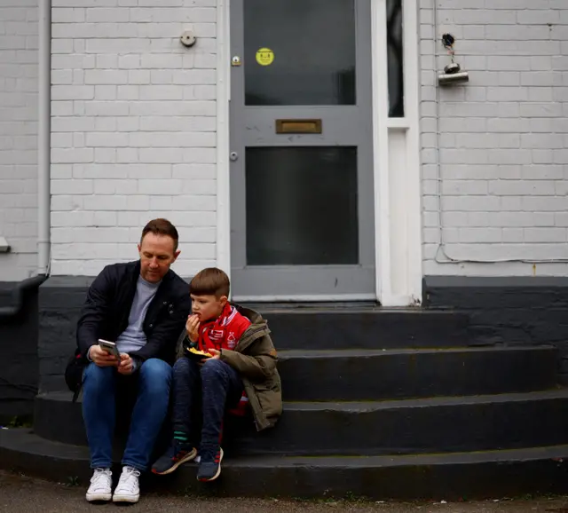 A dad and son sit on steps nearby the city ground