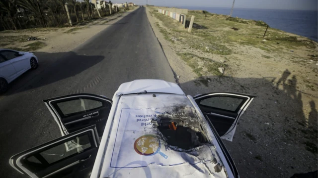 A photo showing a vehicle with a jagged hole in its roof on a road