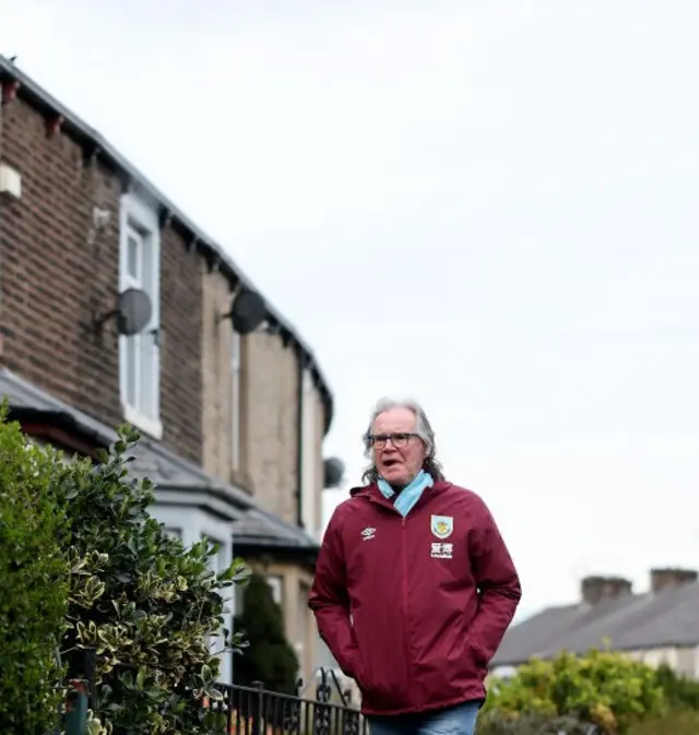 A Burnley fan walks through the terraced houses to Turf Moor