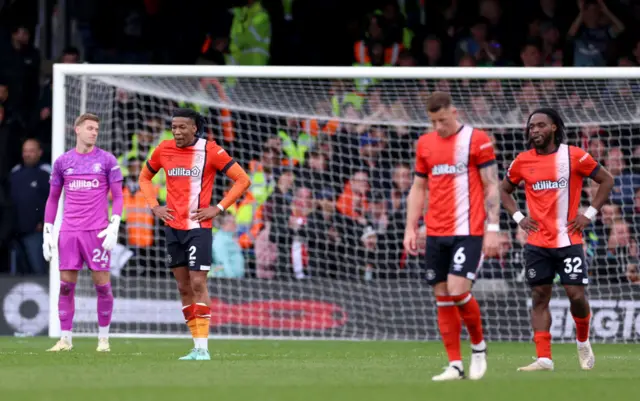 Luton players stand dejected after the fifth Brentford goal