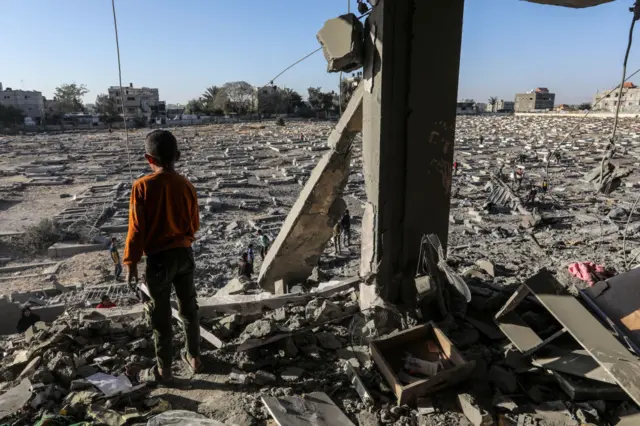 A boy looks out across land where buildings have been demolished