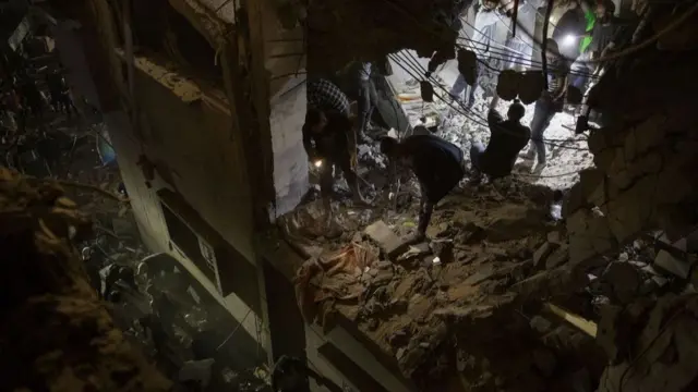 People pictured searching amongst the rubble at a destroyed building in Rafah