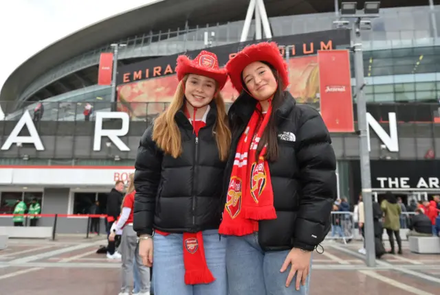 Fans in Arsenal cowboy hats pose outside the emirates