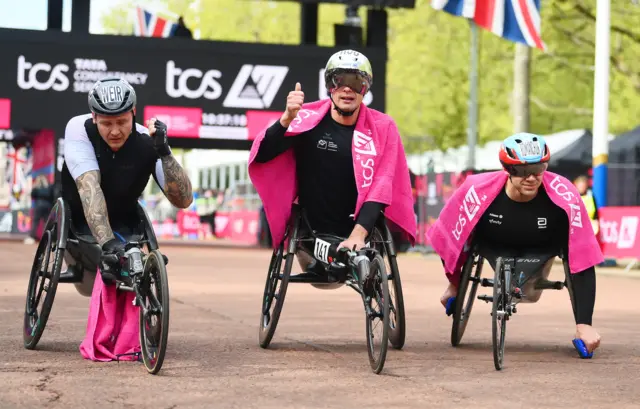 Third placed David Weir of Great Britain, first placed Marcel Hug of Switzerland and second placed Daniel Romanchuk of USA celebrate after the Men's wheelchair race during the 2024 TCS London Marathon